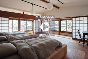 a living room with four beds in a room with windows at 三笠館Mikasakan 本館 in Kinokawa