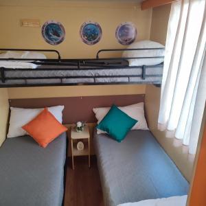 two beds in a small room with pillows at GoldenSand mobilehome in Lido di Dante