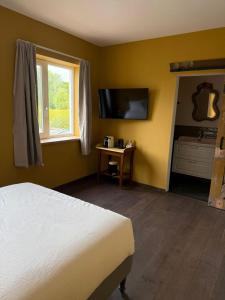 a bedroom with a bed and a tv and a window at L'Hopster Dorpsbrouwerij in Loppersum