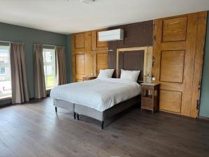 a bedroom with a large bed and a wooden door at L'Hopster Dorpsbrouwerij in Loppersum