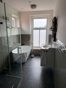 a bathroom with a tub and a shower and a sink at L'Hopster Dorpsbrouwerij in Loppersum
