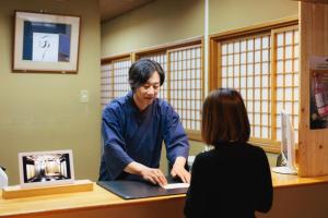 a woman is talking to a woman at a desk at Ryokan Warabino in Takayama