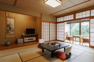 a living room with a table and a tv at Ryokan Warabino in Takayama