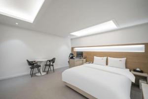 a bedroom with a large bed and a desk and chairs at 드므호텔 in Changwon