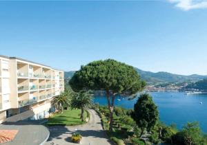 a building with a tree next to a body of water at JR Resort Elba International in Capoliveri