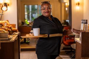 a woman holding a tray with a plate of food at Hotel Des Deux Continents in Paris