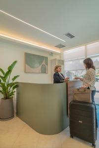 Zwei Frauen stehen mit Gepäck an einem Schalter in einem Büro. in der Unterkunft Telesilla Hotel in Kontokali + 96 Fotos