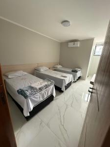 two beds in a room with marble floors at Hotel Impactus Santo Amaro in São Paulo