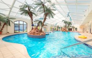 a large swimming pool with palm trees in a building at Dawlish Warren Holidays in Dawlish