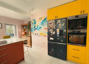 a kitchen with yellow cabinets and a black refrigerator at The Nest in Bristol +11 photos