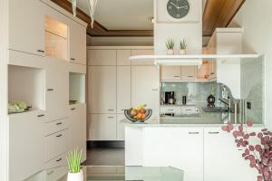 a kitchen with white cabinets and a clock on the wall at Green Eifel Casa in Feusdorf +9 photos