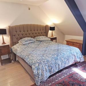 a bedroom with a bed with a blue bedspread and two lamps at B&B Chez Paz in Neer