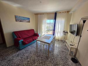 a living room with a red couch and a table at apartamentos la villa in San Sebastián de la Gomera
