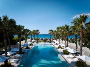 a swimming pool with chairs and palm trees and the ocean at Amadria Park Beach Hotel Jure in Šibenik