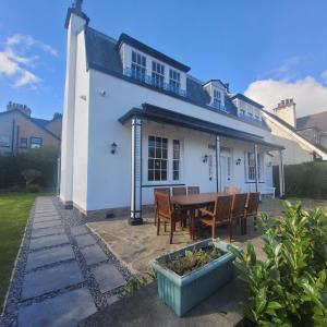 a white house with a table and chairs at Luxury 6 bed house by the sea in Rhos-on-Sea