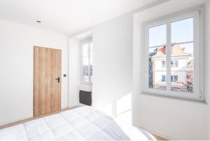 a white bedroom with a door and a window at La Belle Echappée - Superbe T2 en Hyper Centre in Thonon-les-Bains
