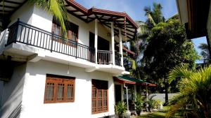 a white building with a balcony and trees at Premier Villa Tangalle in Tangalle