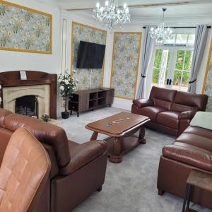 a living room with leather furniture and a fireplace at Luxury 6 bed house by the sea in Rhos-on-Sea