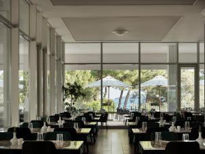 a restaurant with tables and chairs and large windows at Amadria Park Beach Hotel Niko in Šibenik