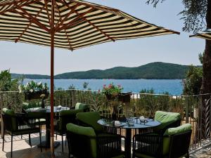 a patio with tables and chairs under an umbrella at Amadria Park Beach Hotel Niko in Šibenik