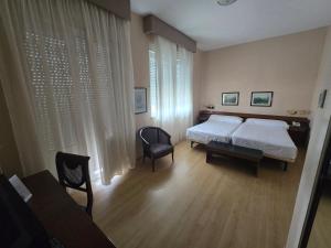 a bedroom with two beds and a table and a chair at Hotel Las Sirenas in Viveiro +14 photos