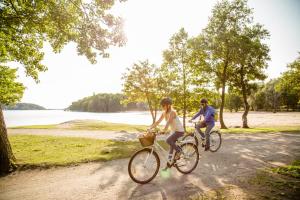 two people riding bikes down a dirt road next to a lake at Original Sokos Hotel Kupittaa in Turku +48 photos