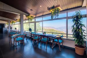 a restaurant with tables and chairs and a large window at Harmony Palace in Mahabaleshwar