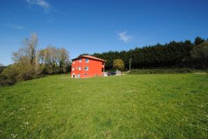 a red house on top of a green field at As Neveiras in Millerada