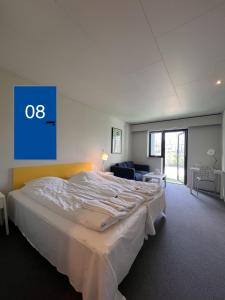a large bed in a room with a blue sign on the wall at Hotel Margrethe in Gadbjerg +9 photos