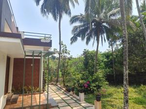 a porch of a house with palm trees at The Riverside Nook Calicut in Kozhikode