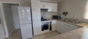 a kitchen with white cabinets and a white refrigerator at Drommedaris in Gordonʼs Bay