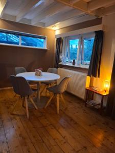 a dining room with a table and chairs and two windows at Fully equipped private guesthouse for up to 4 guests, quiet countryside location, only 30 minutes from Rotterdam, free parking, WiFi and large garden in Klaaswaal