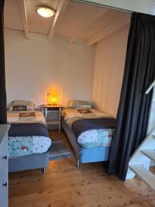 a bedroom with two beds and a table with a lamp at Fully equipped private guesthouse for up to 4 guests, quiet countryside location, only 30 minutes from Rotterdam, free parking, WiFi and large garden in Klaaswaal