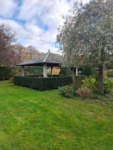 a garden with a gazebo in the middle of a yard at Fully equipped private guesthouse for up to 4 guests, quiet countryside location, only 30 minutes from Rotterdam, free parking, WiFi and large garden in Klaaswaal