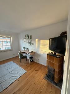 a living room with a flat screen tv and a desk at Gästezimmer in Hafennähe in Waren