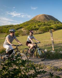 two people riding bikes on a dirt road in a field at Resort Oblík - Luxusní stanové městečko in Raná
