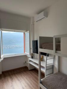 a room with bunk beds with a window and a television at Monolocale Riva Lake in Valbrona