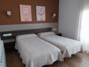 two beds in a hotel room with white sheets at Pension Begoña in Arzúa
