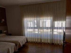 a bedroom with two beds and a large window at Pension Begoña in Arzúa