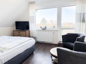 a bedroom with a bed and a chair and a window at Haus Ausreißer 2 - Ankerplatz in Bensersiel