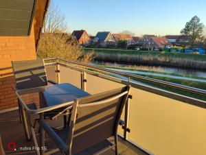 a table and chair on a balcony with a view of a river at Haus Ausreißer 2 - Ankerplatz in Bensersiel