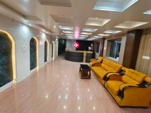 a living room with a yellow couch in a lobby at Hotel Baba Palace in Deoghar
