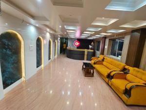 a lobby with a yellow couch in a building at Hotel Baba Palace in Deoghar