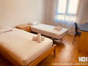 a room with two beds and a desk and a window at Duque de Ahumada 8 in Soria