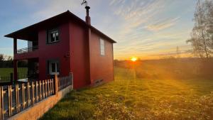 a red house in a field with the sunset in the background at As Neveiras in Millerada