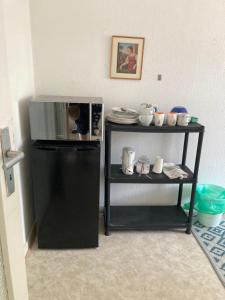 a small black refrigerator next to a shelf with dishes at Self check in ganzes Apartment 40 m zwei Schlafzimmer Wlan Parkplatz eigenes Badezimmer mit Badewanne Kochecke Einfamilienhaus in Duisburg