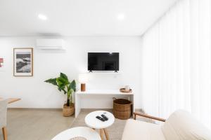 a living room with white furniture and a tv on the wall at Big Waves Retreat Nazaré - By Nest & Co in Nazaré