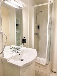 a white bathroom with a sink and a shower at Logis Hotel restaurant de la Poste in Pontgibaud +22 photos
