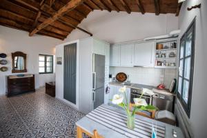 a kitchen with white cabinets and a table with flowers on it at Aegean Dream in Klíma