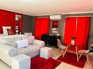 a living room with a couch and a bed with red curtains at Clifford's Rufaro Hotel, Conference & Spa in Burgersfort